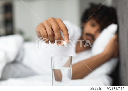 Eastern man suffering from headache, taking pills Eastern man suffering from headache, taking pills 93138742