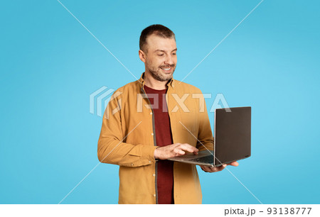 Successful Freelancer Male Using Laptop Computer Over Blue Studio Background Successful Freelancer Male Using Laptop Computer Over Blue Studio Background 93138777