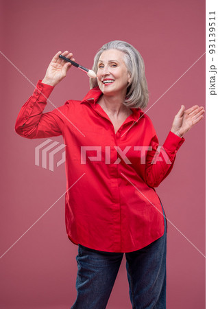 Smiling woman in red with a face brush in hand Smiling woman in red with a face brush in hand 93139511