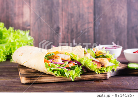 Mexican tortilla wraps with chicken and vegetables on a board on the table 93141857