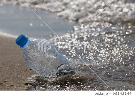 Close-up, selective focus, transparent PET plastic bottle with blue cap garbage left away on sandy beach Close-up, selective focus, transparent PET plastic bottle with blue cap garbage left away on sandy beach 93142144