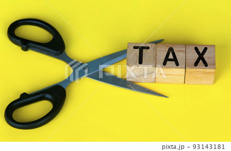 Scissor cutting wooden blocks with text TAX. Cutting tax expenses concept. 93143181