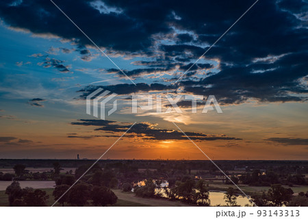 Rural landscape with river and city on the horizon, at sunset. Rural landscape with river and city on the horizon, at sunset. 93143313