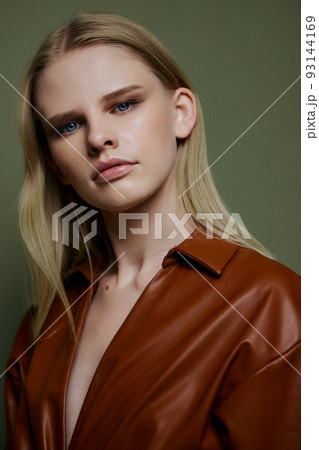 Closeup portrait of fashionable expressive professional blonde female model. Beautiful woman looks at camera posing isolated on green background 93144169