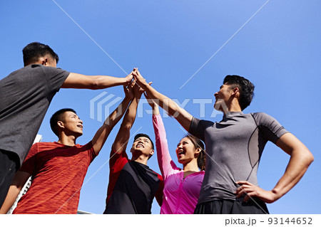 team of asian young adult sportsmen and sportswoman putting hands together to show unity and teamwork spirit 93144652