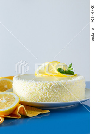 Lemon cake with coconut flakes on blue background. Delicate dessert with cream. Lemon cake with coconut flakes on blue background. Delicate dessert with cream. 93144830