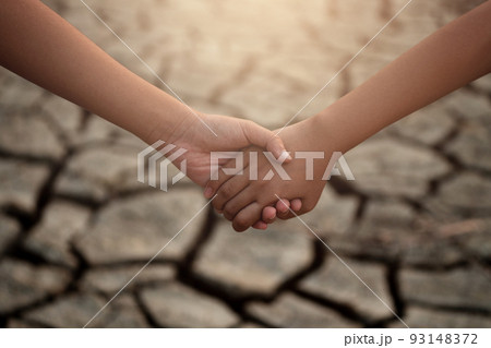 Young boy and girl holding hands on cracks in the dried soil in arid season. Saving environment and natural conservation concept. Young boy and girl holding hands on cracks in the dried soil in arid season. Saving environment and natural conservation concept. 93148372