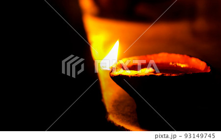 Close up image of a lit clay diya or lamp on floor on Diwali - an Indian hindu festival of lights isolated on black background. 93149745