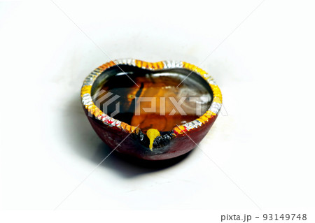 Close up image of a lit clay diya or lamp on floor on Diwali - an Indian hindu festival of lights isolated on black background. 93149748