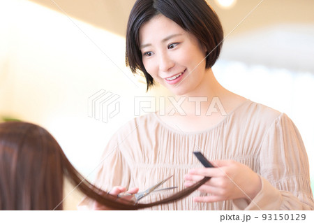 美容室でお客の髪をカットする女性ヘアスタイリスト 93150129