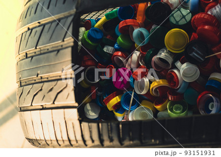 Public place collecting in car tire full of colorful plastic bottle cups, handful of waste of plastic lids. Recycling. Collecting bottle caps. Environment concept plastic bottle cap that is left from Public place collecting in car tire full of colorful plastic bottle cups, handful of waste of plastic lids. Recycling. Collecting bottle caps. Environment concept plastic bottle cap that is left from 93151931
