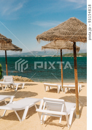 Deck chairs with straw parasols near the river 93154818