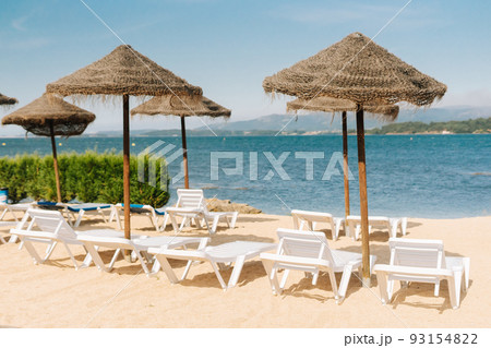 Deck chairs with straw parasols near the river Deck chairs with straw parasols near the river 93154822