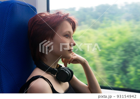 girl rides on a commuter train and looks out the window at a natural landscape blurred in motion 93154942