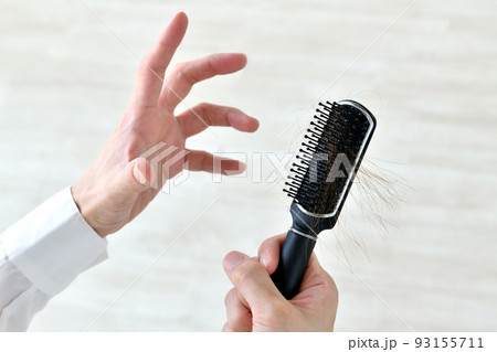 抜け毛・切れ毛にショックを受ける人物の手元 93155711