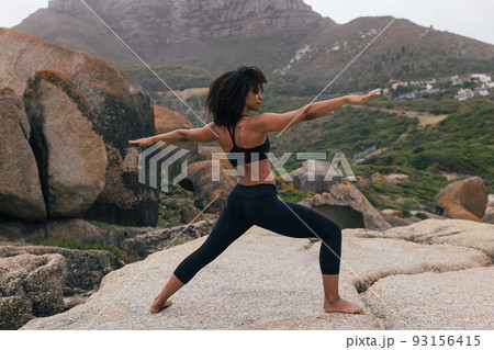 Full length of young woman doing warrior pose against beautiful landscape at sunset Full length of young woman doing warrior pose against beautiful landscape at sunset 93156415