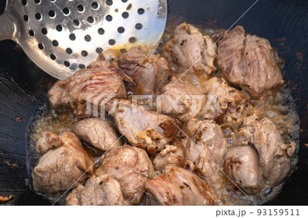 Large chunks of lamb sheep fried in oil with bubbles in a black cauldron close-up Large chunks of lamb sheep fried in oil with bubbles in a black cauldron close-up 93159511