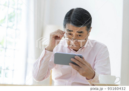 メガネをずらしてスマホを見るシニア男性 メガネをずらしてスマホを見るシニア男性 93160432