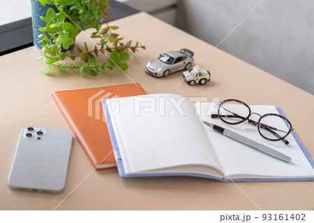 デスクに置いてあるノートとペンとメガネ 93161402