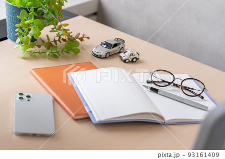 デスクに置いてあるノートとペンとメガネ 93161409