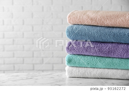 Stack of clean bath towels on white marble table. Space for text 93162272