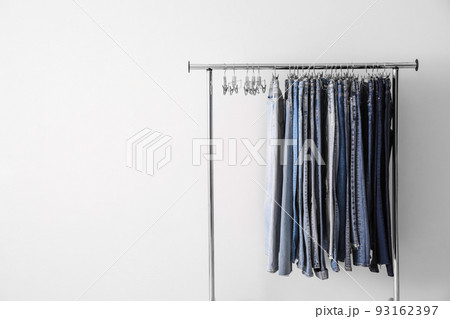 Rack with different jeans on white background. Space for text 93162397