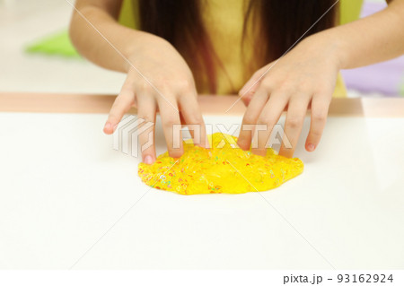 Little girl playing with slime at white table, closeup 93162924