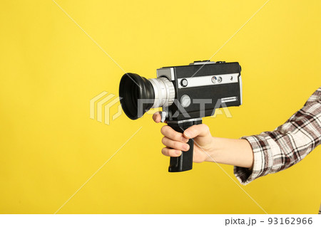Woman with vintage video camera on yellow background, closeup of hand 93162966