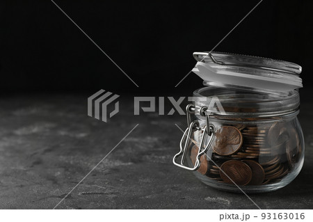 Glass jar with coins on grey table, space for text Glass jar with coins on grey table, space for text 93163016