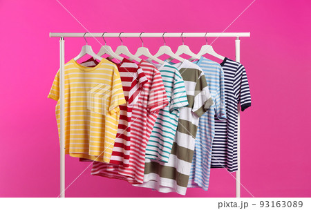 Colorful clothes hanging on rack against pink background 93163089
