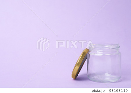 Open empty glass jar on lilac background, space for text Open empty glass jar on lilac background, space for text 93163119