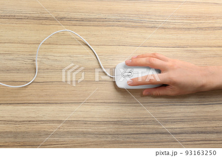 Woman using modern wired optical mouse on wooden table, top view 93163250