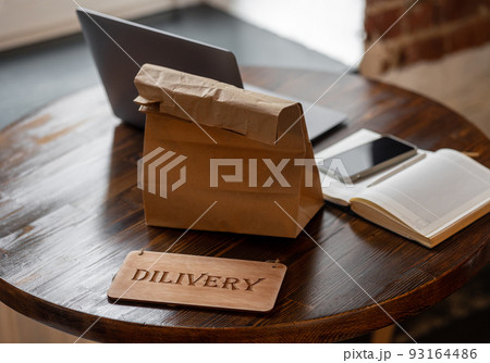 there is ready-made food and drinks on the table in a restaurant or delivery service. to the courier, pizza or fast food packed in a paper bag 93164486