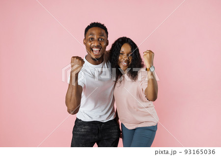 Big win. Happy excited african couple celebrating success with raised fists. 93165036