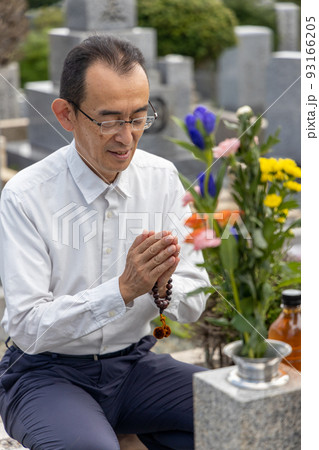 お墓参りをして手を合わせているシニア男性 お墓参りをして手を合わせているシニア男性 93166205