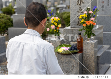 お墓参りをして手を合わせているシニア男性 93166213