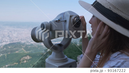 Woman traveler looking at city view, close-up. Beautiful woman in hat, on observation watching through telescope at city Tirana panorama. Mountain Dajti, Albania Woman traveler looking at city view, close-up. Beautiful woman in hat, on observation watching through telescope at city Tirana panorama. Mountain Dajti, Albania 93167222