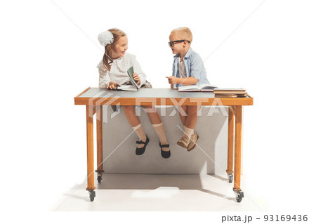 Portrait of little boy and girl, children sitting at desk and studying, doing homework isolated over white background Portrait of little boy and girl, children sitting at desk and studying, doing homework isolated over white background 93169436