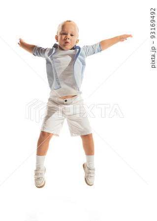 Portrait of little boy, child in casual outfit posing isolated over white studio background. Cheerfully jumping, playing Portrait of little boy, child in casual outfit posing isolated over white studio background. Cheerfully jumping, playing 93169492