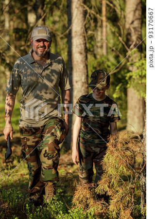 Father and son in military clothes spending time together in the woods. The concept of adventure, travel, tourism and camping Father and son in military clothes spending time together in the woods. The concept of adventure, travel, tourism and camping 93170667