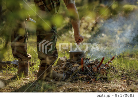 Cooking food in pot on campfire..The concept of adventure, travel, tourism, camping, survival and evacuation. 93170683