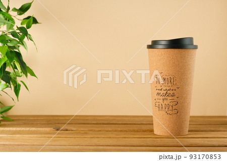 A takeaway coffee cup made of cork wood with a positive inscription on the table on a beige-brown background 93170853
