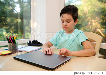 Beautiful child, teenage school boy sitting at laptop, getting ready for an online lesson in a new semester of new academic year. Back to school. Online education. Knowledge. Copy ad space 93171291