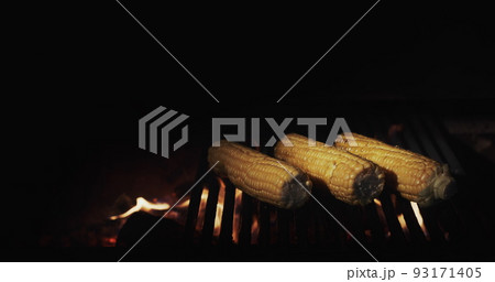 Cooking on an open fire - delicious corn is fried on a hot grill in the grill Cooking on an open fire - delicious corn is fried on a hot grill in the grill 93171405