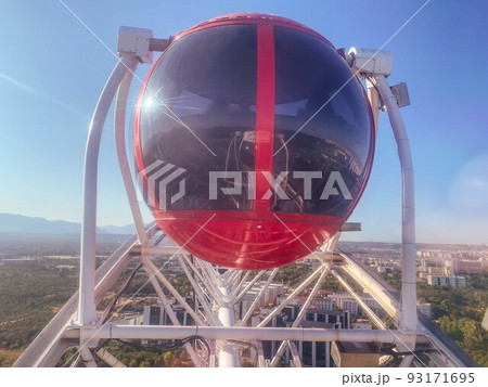 on the Ferris wheel there are large cabins for skiing tourists of red color with tinted black windows. attraction sightseeing tour 93171695