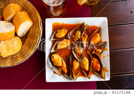 Picture of baked tasty mussels with sauce at plate on table 93175196