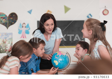Female teacher with kids in geography class looking at globe. Side view of group of diverse happy school kids with globe in classroom at school. Female teacher with kids in geography class looking at globe. Side view of group of diverse happy school kids with globe in classroom at school. 93176633
