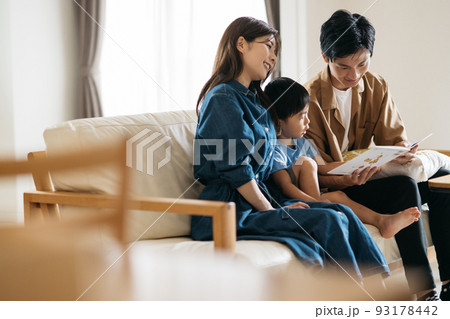 ソファに座る笑顔の日本人家族・絵本を見るファミリー 93178442