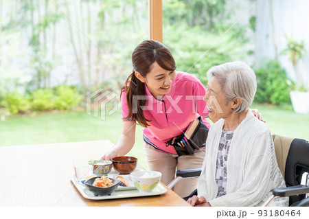 食事するシニア女性とヘルパーの女性 93180464