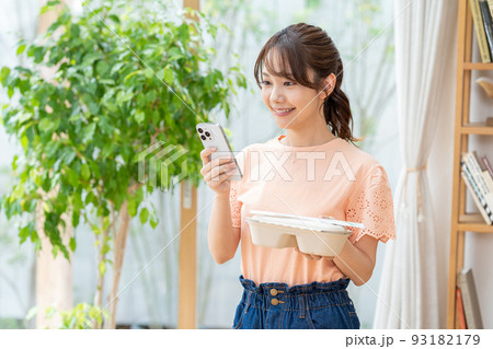 お弁当とスマホを持つ若い女性 93182179